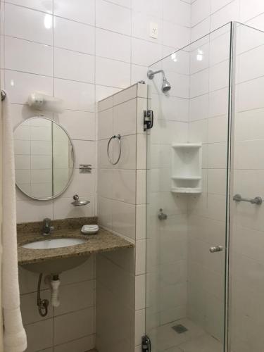 a bathroom with a shower with a sink and a mirror at Hotel Nosso Sonho in Itatiba