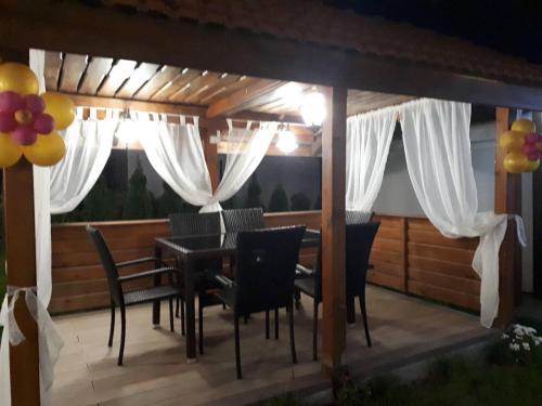 a wooden deck with a table and chairs and curtains at Вила Поликсения Петиня in Tryavna