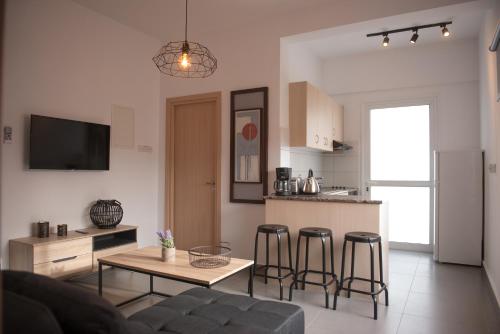 a living room with a couch and a table and a kitchen at MCPlaces Holiday Apartments in Paphos City