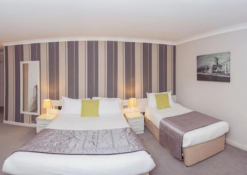 Una habitación de hotel con dos camas y dos lámparas. en Ardree House B&B, en Killarney