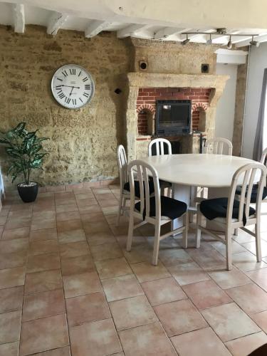 une salle à manger avec une table, des chaises et une horloge dans l'établissement Maison de charme, à Concourson-sur-Layon