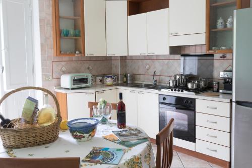 a kitchen with white cabinets and a table with a bottle of wine at Melina's House in Tramonti