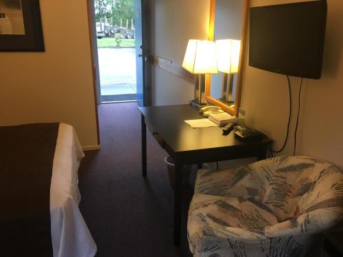 a hotel room with a desk with a bed and a mirror at Fuller Lake Chemainus Motel in Chemainus