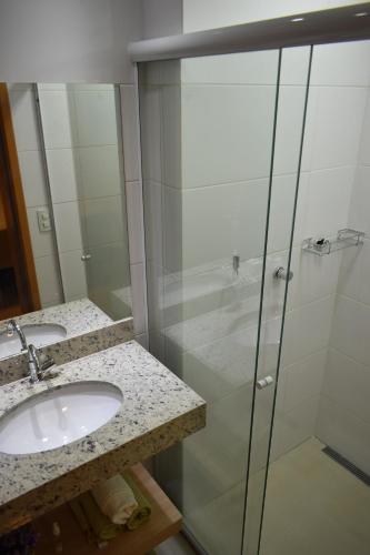 a bathroom with two sinks and a glass shower at Everest Flat Service in Caldas Novas