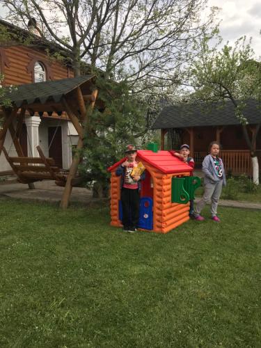 three children standing in a play house in the grass at Guest House Perlyna in Verkhovyna