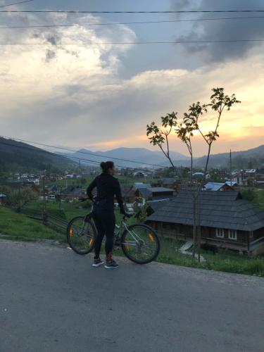 a person standing with a bike on a road at Guest House Perlyna in Verkhovyna