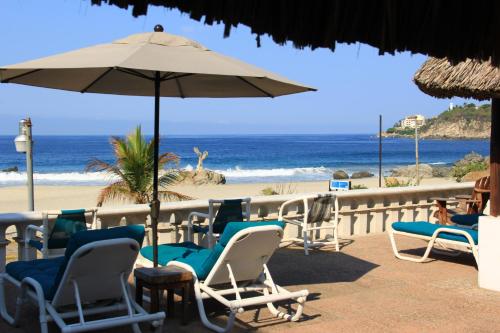 een strand met stoelen en een parasol en de oceaan bij Hotel Santa Fe in Puerto Escondido