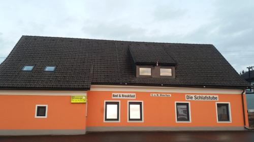 a small orange building with a black roof at Die Schlafstube - Bed & Breakfast in Zeltweg