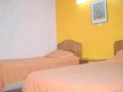 two beds in a room with yellow walls at Hotel Capric in Viña del Mar