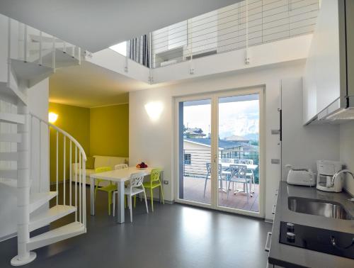 eine Küche und ein Esszimmer mit einem Tisch und einem Balkon in der Unterkunft Gardabike Residence in Nago-Torbole