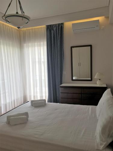 a bedroom with a large white bed with a mirror at Grace Apartments in Loutraki
