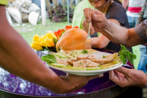 a person holding a plate of food with a sandwich at Posada Las Bromelias in Silvania