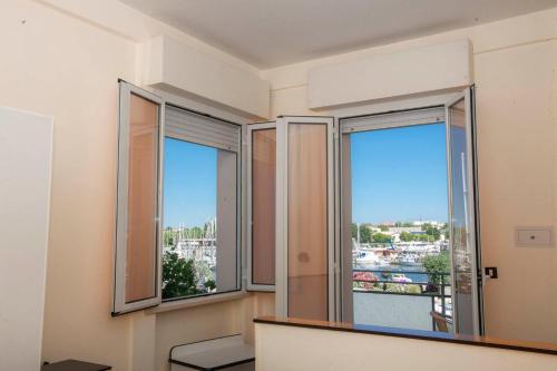 a room with two windows with a view of a city at Hotel Baltic in Cesenatico