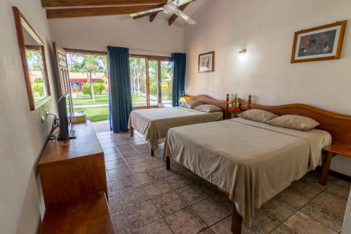 Hotel Guanacaste Lodge في بلايا فلامنغو: غرفة نوم بسريرين ونافذة