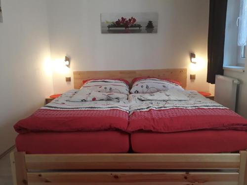 a bed with a red and white quilt on it at Moderni Domek Lipno in Lipno nad Vltavou
