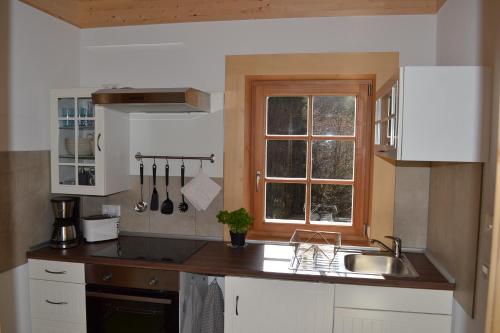 uma cozinha com armários brancos, um lavatório e uma janela em Ferienwohnung Brox em Sebnitz