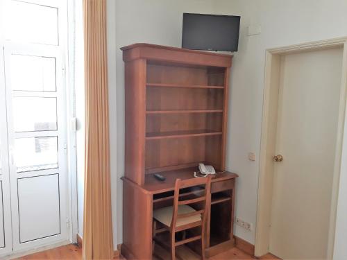 a wooden book shelf with a television on top of it at Hotel Alianca in Figueira da Foz
