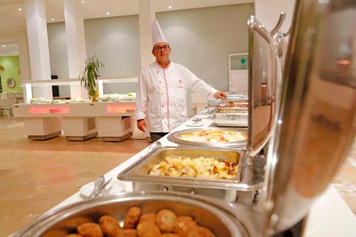 a chef standing in a kitchen preparing food at Hello Yasmine Hotel in Hammamet