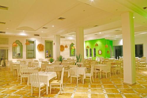 a restaurant with white tables and chairs and green walls at Hello Yasmine Hotel in Hammamet