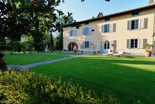 une grande maison avec une pelouse verte en face de celle-ci dans l'établissement Borgo Ai Lecci, à Orentano