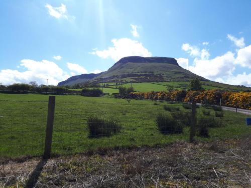a field with a fence in front of a mountain at Red Bay Holiday Home in Cushendall