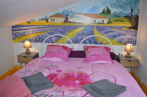 ein Bett mit rosa Bettwäsche und einem Gemälde an der Wand in der Unterkunft Campagn'Art in Les Fosses