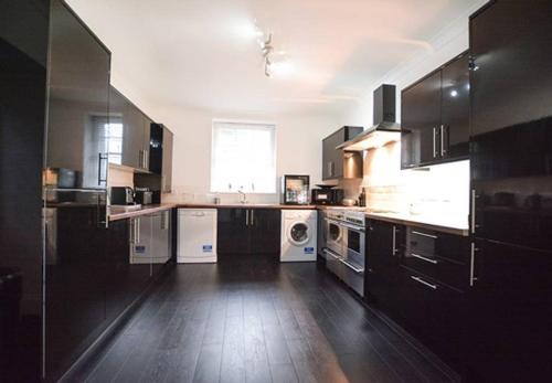 a large kitchen with black cabinets and white appliances at Reivers Apartment in Berwick-Upon-Tweed