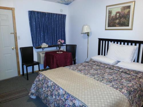 1 dormitorio con 1 cama y 1 mesa con silla en Holiday Motel, en Orillia
