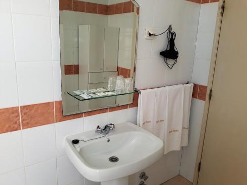 a bathroom with a sink and a mirror and towels at Hotel Alianca in Figueira da Foz