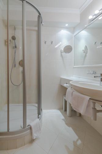 a white bathroom with a shower and a sink at Wohlfühlhotel Schiestl in Fügen