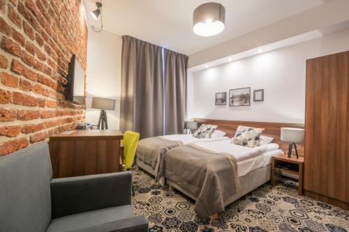 a hotel room with a bed and a brick wall at Hotel Lavender in Kraków