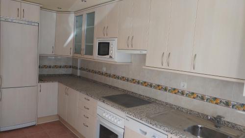 a kitchen with white cabinets and a sink and a microwave at El Mirador de Molinos in Molinos de Duero