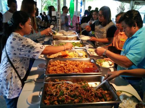 a group of people standing around a buffet table with food at ฺBaan Rai Ing Doi in Chaiyaphum