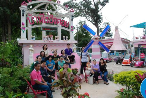 a group of people posing in front of a pink house at ฺBaan Rai Ing Doi in Chaiyaphum