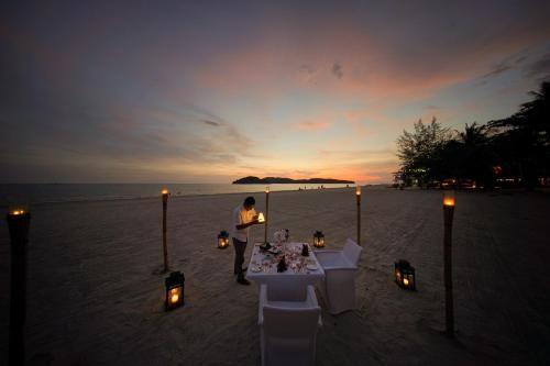 a man standing in front of a table on the beach at Casa del Mar Langkawi in Pantai Cenang