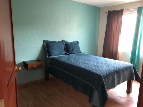een slaapkamer met een bed met blauwe lakens en een raam bij Expo Guadalajara House in Guadalajara