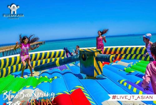 a group of girls jumping on an inflatable play structure at the beach at Chalet in Bluebay Asia Resort Ain Sokhna in Ain Sokhna