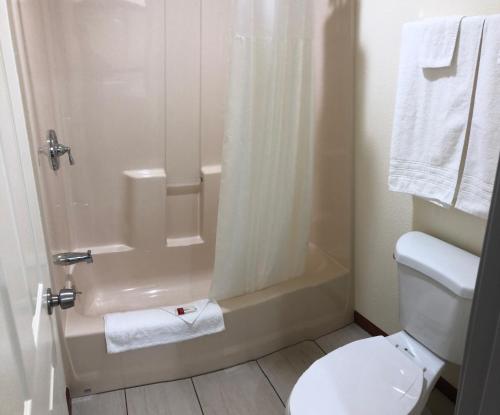 a bathroom with a shower and a toilet and towels at Days Inn by Wyndham Oroville in Oroville
