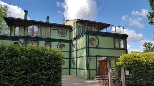 a green building with a clock on it at Villa Moderna in Jūrmala