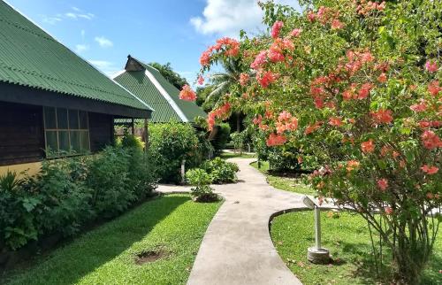 a garden with a walkway next to a house at Pension Les Trois Cascades in Uturoa