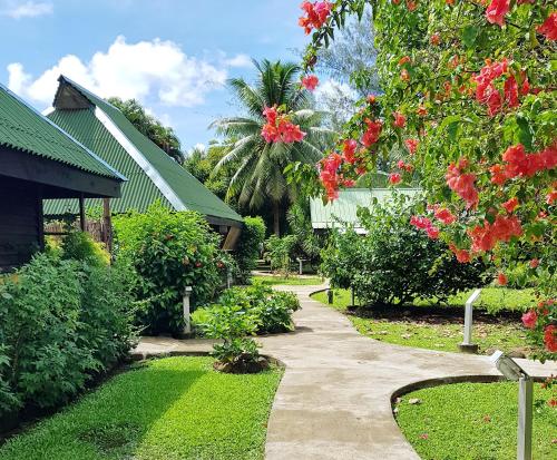 a garden with a path leading to a house at Pension Les Trois Cascades in Uturoa