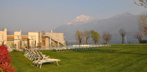 a row of chairs in a field with a building at Tullio Hotel in Gravedona