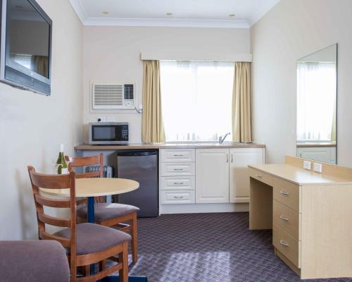 a small kitchen with a table and a table and chairs at Blue Mountains Heritage Motel in Katoomba