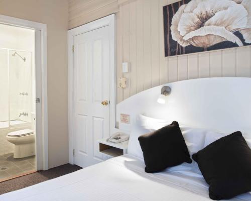 a bedroom with a bed and a bathroom with a toilet at Blue Mountains Heritage Motel in Katoomba