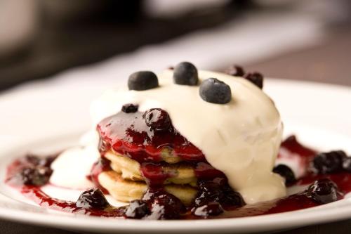 a piece of cake with blueberries and whipped cream on a plate at Distant Hills Guest House in Spean Bridge