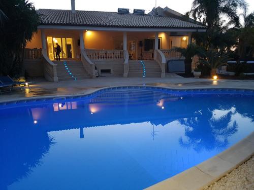 una casa con una piscina azul frente a una casa en villa Bismarkia, en Siracusa