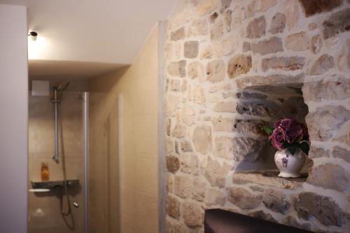 a bathroom with a stone wall with a vase on a fireplace at Apartments Dvor - ap1, ap2, ap3 in Baška Voda