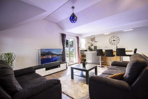 ein Wohnzimmer mit 2 Sofas und einem Flachbild-TV in der Unterkunft Apartments Dvor - ap1, ap2, ap3 in Baška Voda