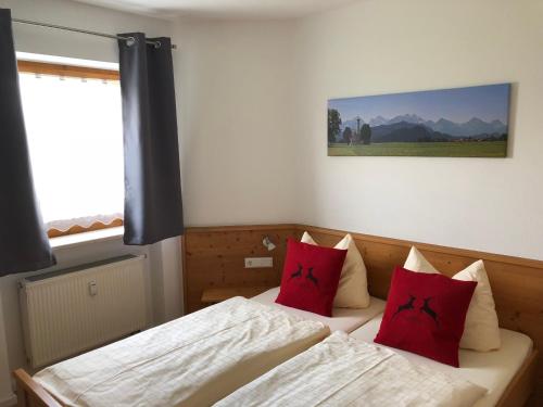 シュヴァンガウにあるFerienwohnung Hoferのベッドルーム1室(赤い枕のベッド2台付)