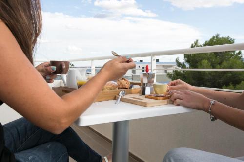 two women sitting at a table with a tray of food at Via Del Faro Apartments in Torre Canne